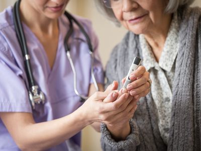 Doctor showing older woman how to take measure blood sugar