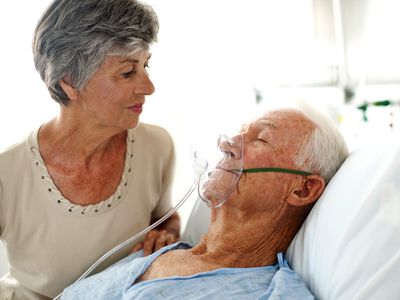 Woman looking at her husband wearing an oxygen mask