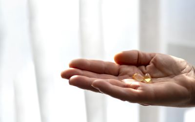 Woman holding vitamin D supplements next to a window