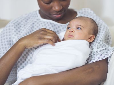 Black woman in hospital gown holding baby