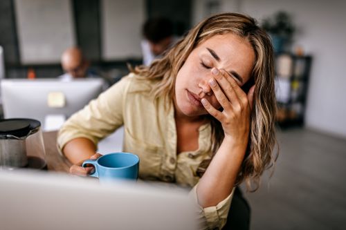 A woman with a hand to her face and the other hand on a mug