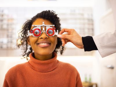 Young woman having eyesight test at optical store. Ophthalmologist hand adjusting the lens degree on trial frame wore by a female client.