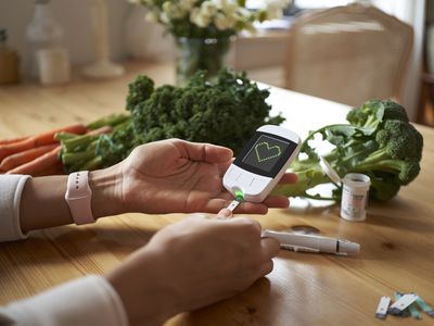 Person checking blood glucose level at home before preparing a meal