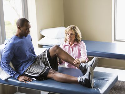 Physical therapist helping man with knee trouble