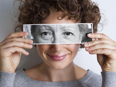 Woman with photo of elderly woman's eyes on hers