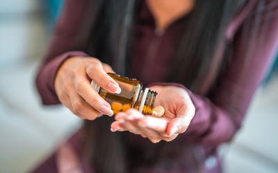 A female pouring tablets into her hand out of supplement bottle