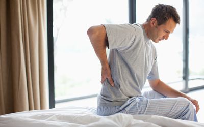 Man with lower back pain sitting on bed