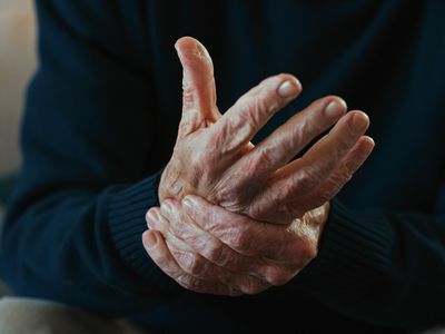 A person holding one hand in another, feeling knuckle pain