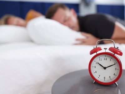 Man and woman sleep in bedroom on alarm clock at ten in morning. Late night sleep weekend concept