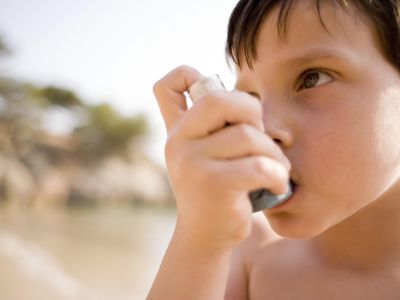 Asthmatic boy (6-7) using inhaler