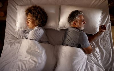 do women need more sleep than men? High angle view of relaxed senior couple sleeping back to back in a bed.