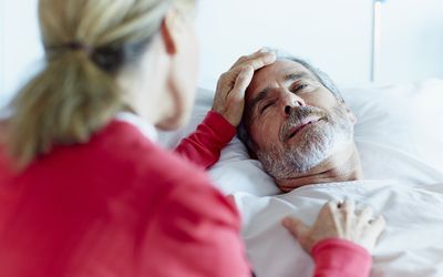 an older woman touching an older man's forehead