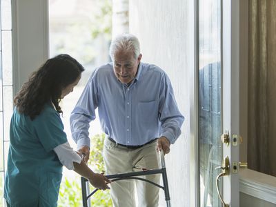 Home healthcare worker helping elderly man with walker