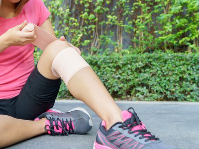 woman applying elastic bandage to knee joint