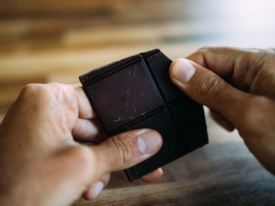 person holding a large square of dark chocolate