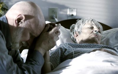 Elderly man with his wife as his wife begins the dying process