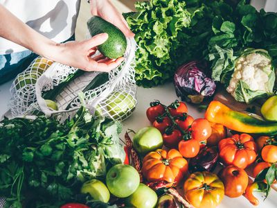 Woman takes fresh vegetables out of mesh bag 