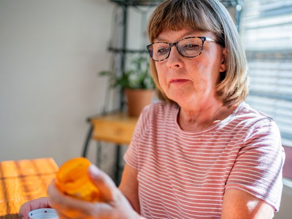 A person reads a prescription bottle at home