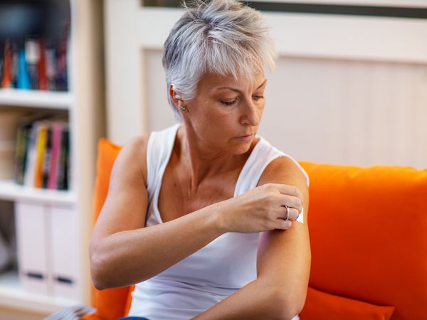 A woman using a transdermal patch for hormone replacement therapy on her arm