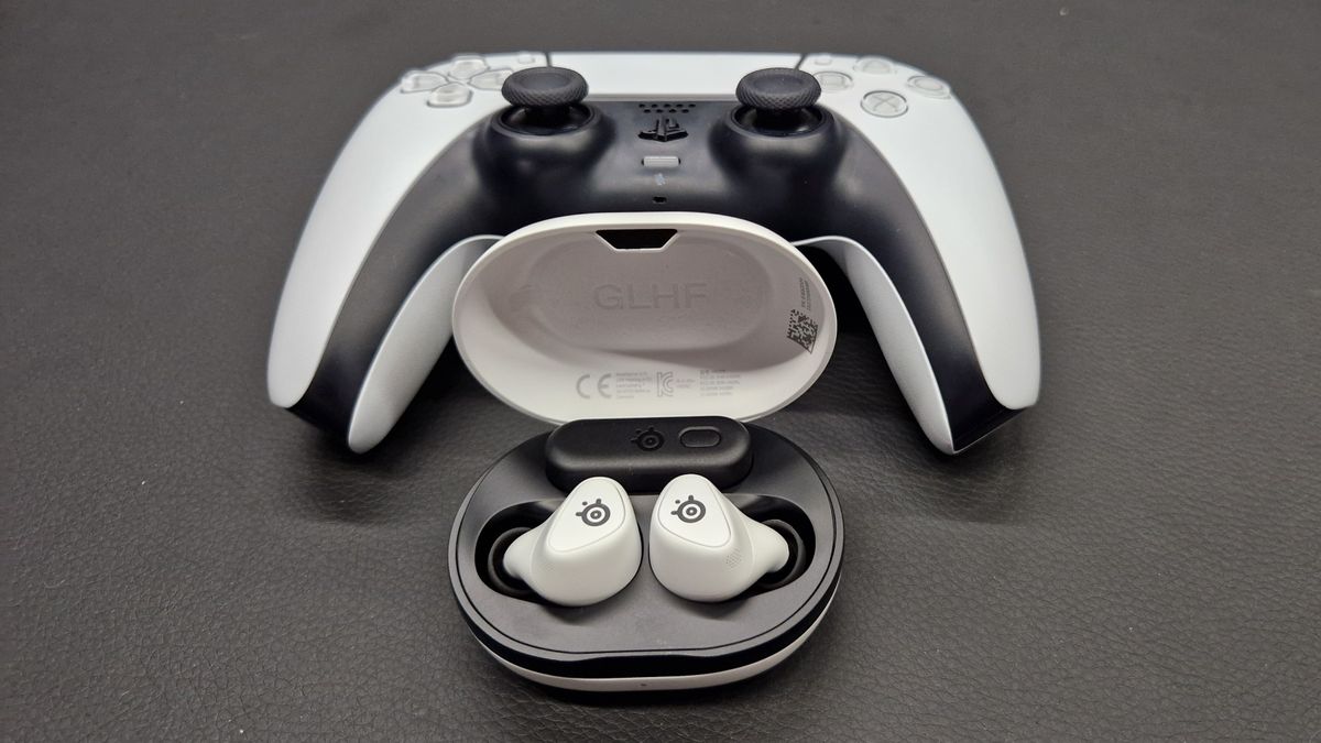 SteelSeries Arctis GameBuds on a black desk in front of a DualSense