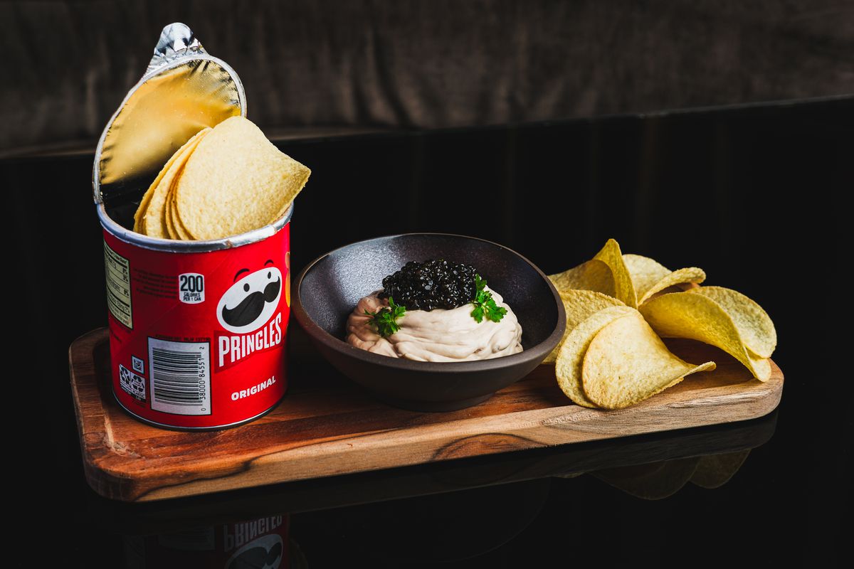 A cup of Pringles brand chips with a bowl of caviar dip. 