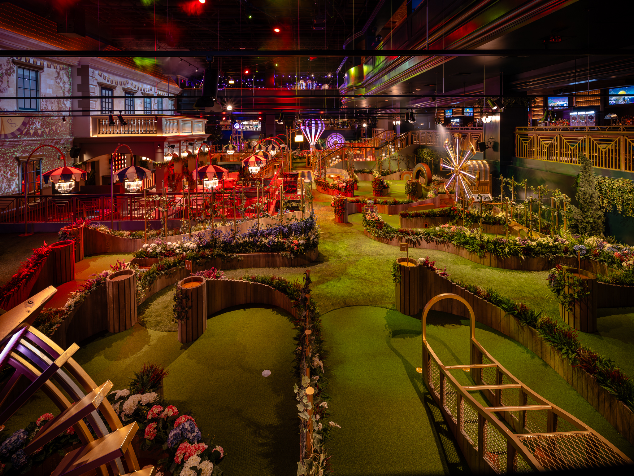 An indoor gold course with colorful lighting and a cocktail bar.