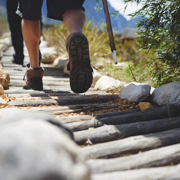 Feet of male hiker hiking along log footpath