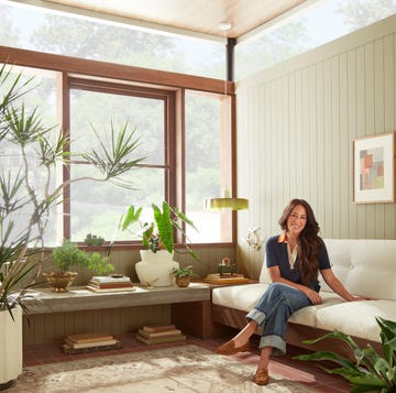 joanna gaines sitting on a couch next to a wall painted in a color from her paint collection