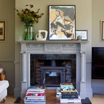 fireplace mantel in suzie de rohan willner house, with an original artwork by her daughter resting on top, including other touches like sculptures, vases, and an oversized green vase filled with flowers