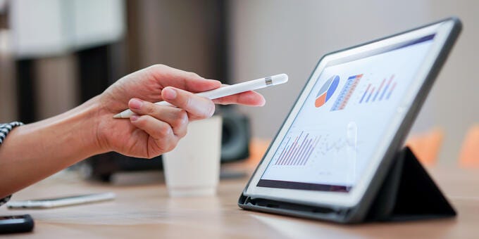 a hand holding a pen and a tablet